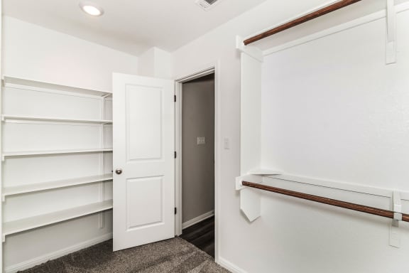 a walk in closet with white walls and a white door
