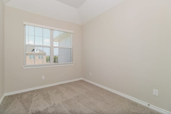 an empty bedroom with a large window and carpeting