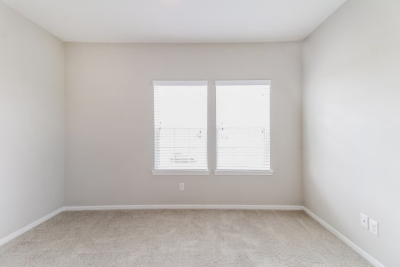 an empty room with two windows in it
