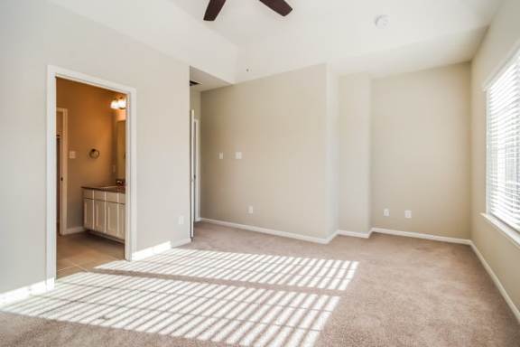 A room with a ceiling fan and a rug on the floor.