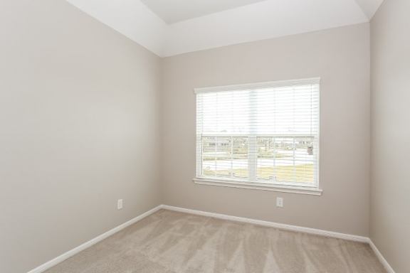 A room with a window and carpeted floor.