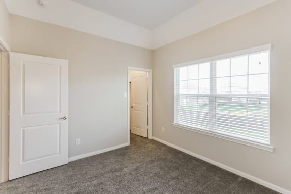 an empty bedroom with a large window and a door