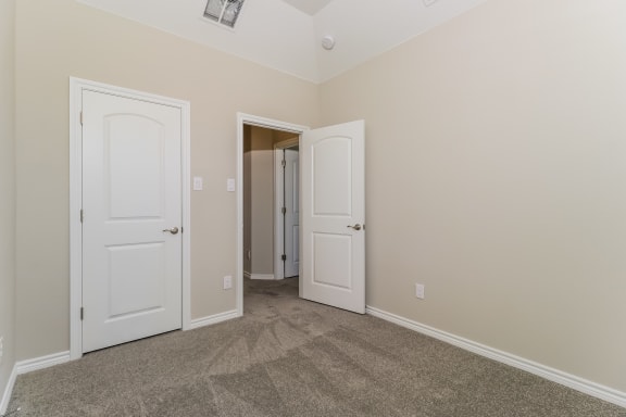 an empty bedroom with two doors and a closet