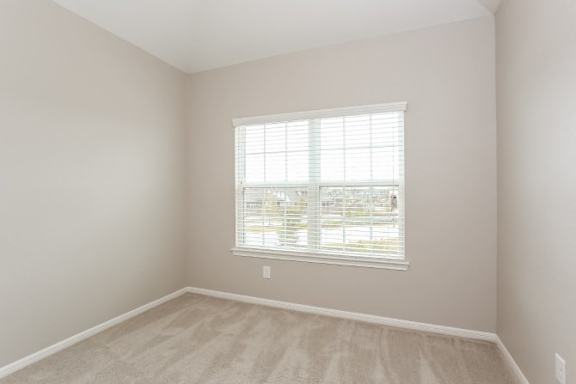 A room with a window and a carpeted floor.