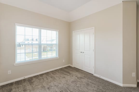 an empty bedroom with a window and a door