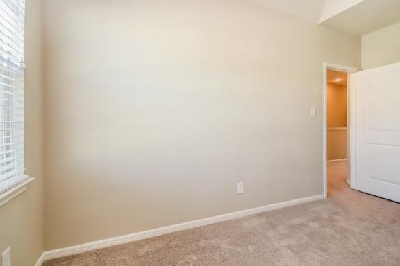 A room with a carpeted floor and a white door.