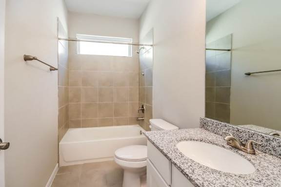 A white toilet sits next to a bathtub in a bathroom.
