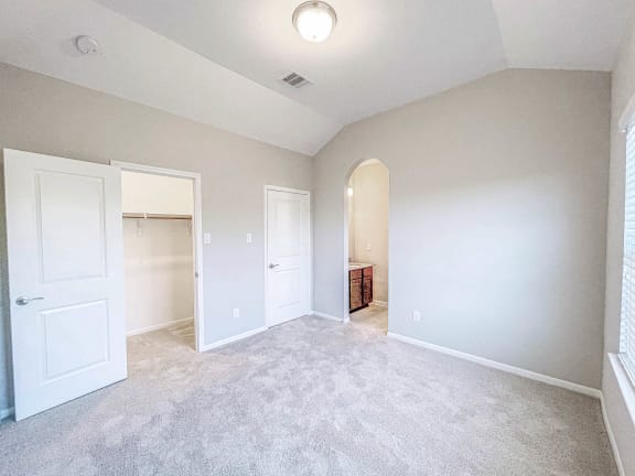 an empty bedroom with white doors and a closet