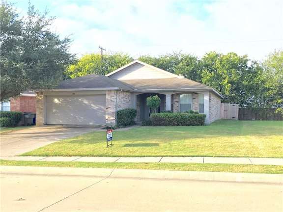 A house with a garage and a sign in front.