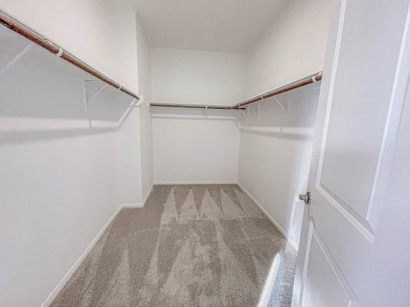 an empty walk in closet with white walls and a door