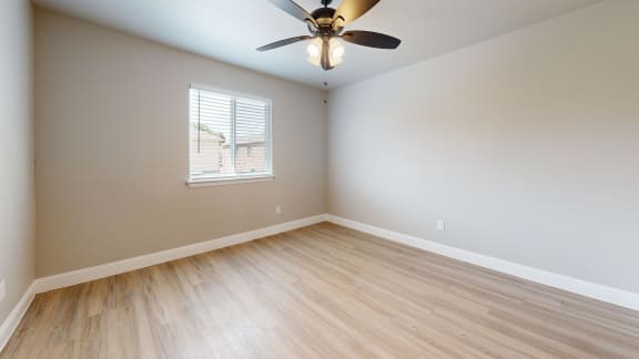 an empty living room with wood floors and a ceiling fan