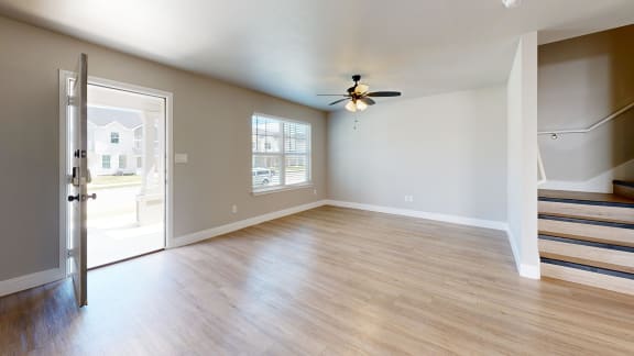 an empty living room with wood floors and a ceiling fan