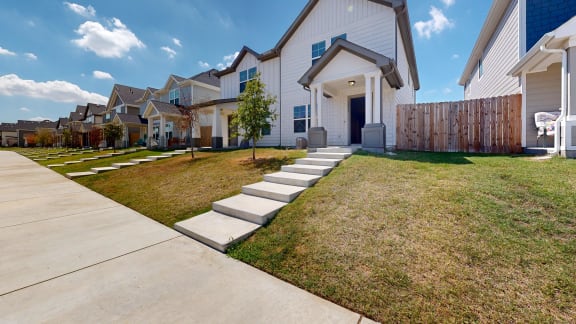 a row of houses with a sidewalk and grass