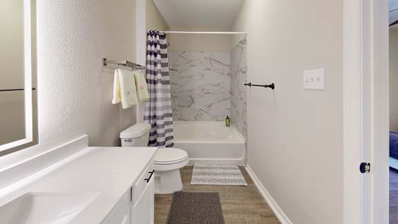 A white bathroom with a marble shower and toilet.