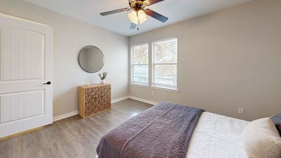 A bedroom with a bed, a ceiling fan, and a window.
