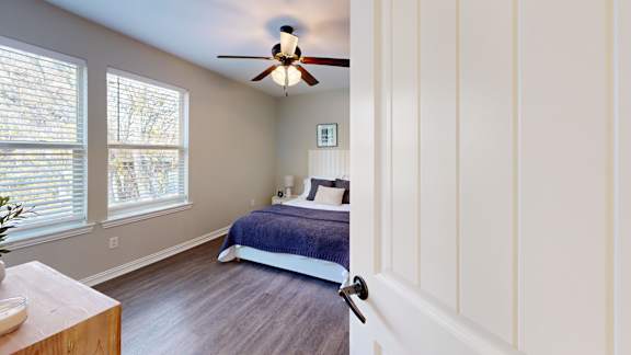 A bedroom with a bed, a ceiling fan, and a window with blinds.