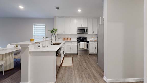A white kitchen with a dining table and chairs.