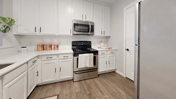 A kitchen with white cabinets and a black stove top.