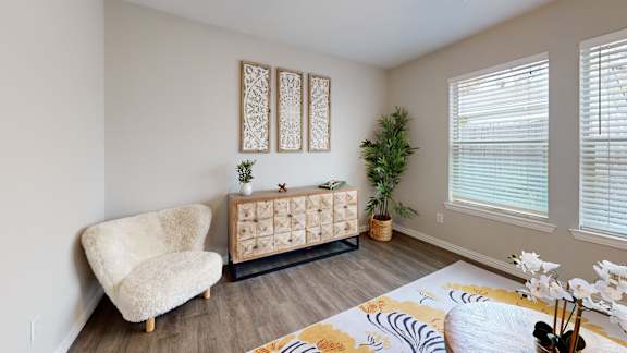 A living room with a white chair, a wooden cabinet, and a rug.