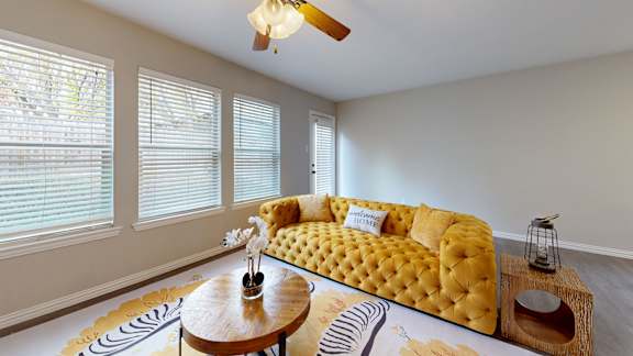 A yellow tufted sofa sits in a room with a wooden coffee table in front of it.