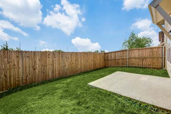 A backyard with a wooden fence and a concrete slab.