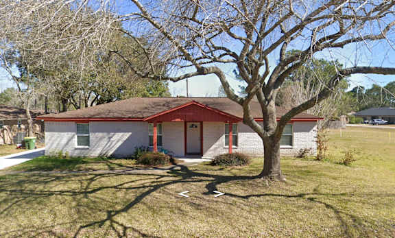 A house with a red roof and a tree in front.