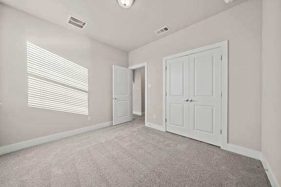 A room with a white door and a carpeted floor.