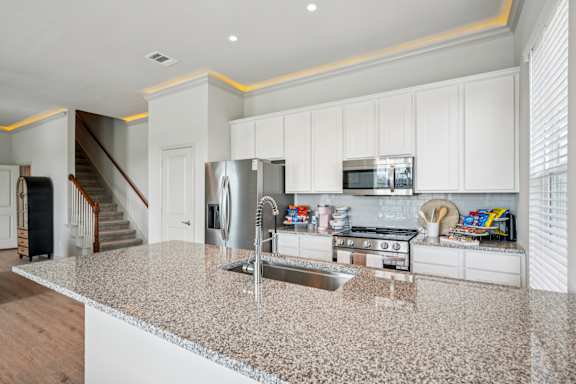 A kitchen with granite countertops and white cabinets.