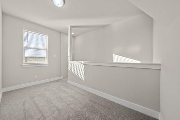 A room with a carpeted floor and a window with blinds.