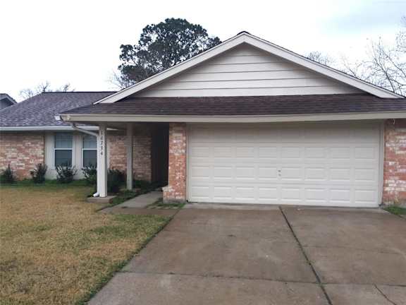A house with a white garage door and a brick wall.
