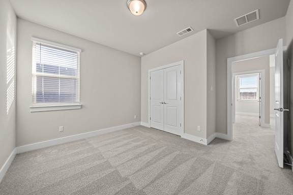 A room with a carpeted floor and a window with blinds.