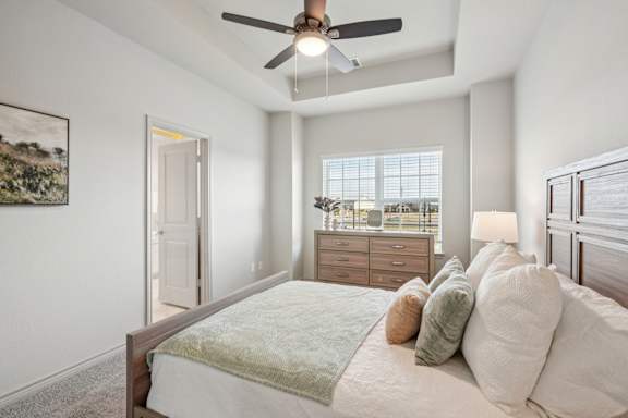A bedroom with a bed, a ceiling fan, and a window with blinds.