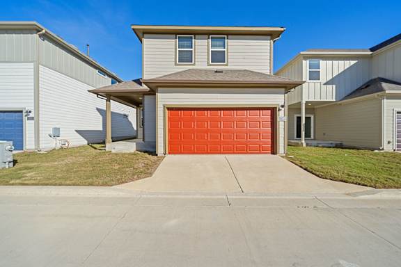A house with a red garage door in front of a blue sky.