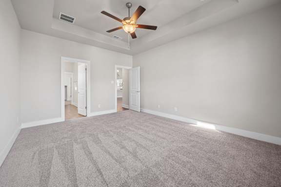 A room with a ceiling fan and carpeted floor.