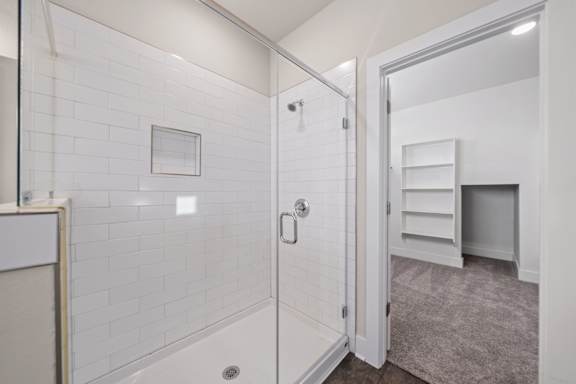 A white bathroom with a white tiled shower and a white door.