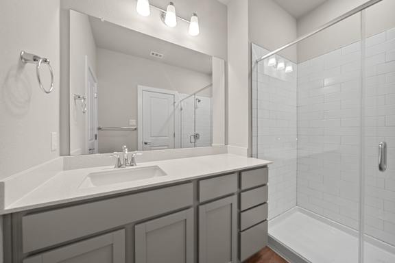A bathroom with a sink, mirror, and shower.