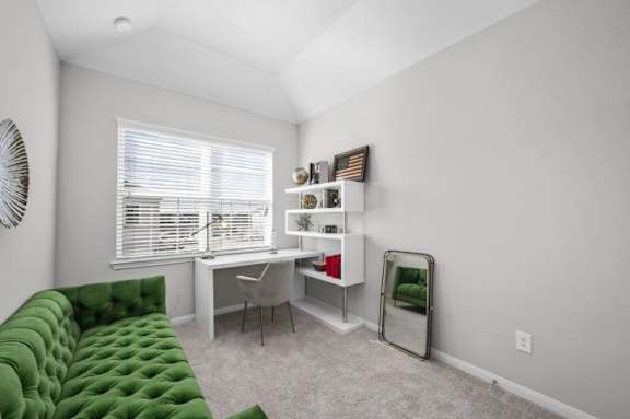 A room with a green sofa, desk, and chair.