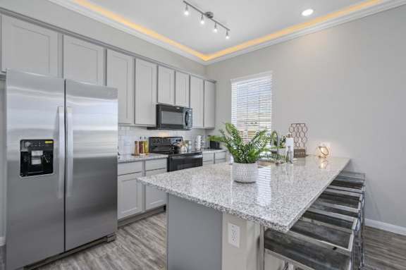 A modern kitchen with a stainless steel refrigerator and a granite countertop.