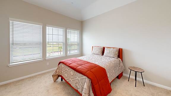 a bedroom with a bed and three windows