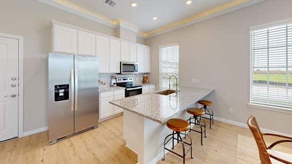 a kitchen with a marble counter top and a stainless steel refrigerator