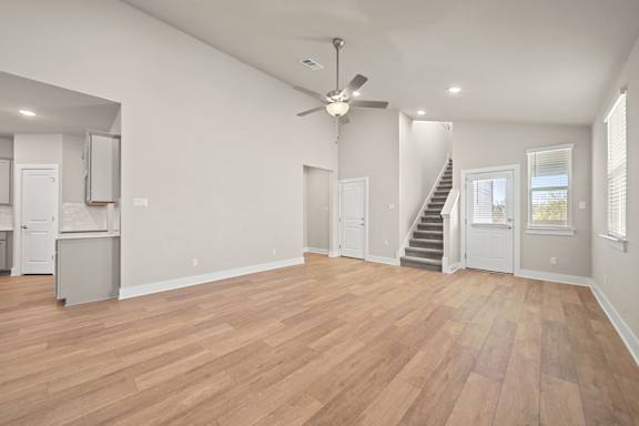 A spacious room with wooden flooring and a ceiling fan.