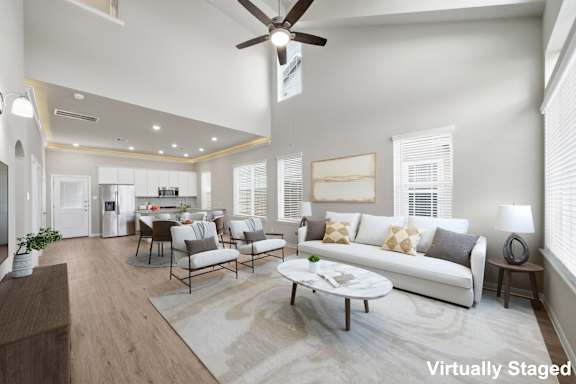 A living room with a white couch, a coffee table, and a ceiling fan.