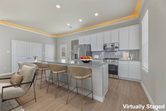 A kitchen with white cabinets and a bar area with stools.