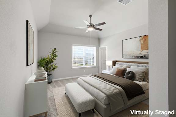 A bedroom with a bed, a fan, and a plant.