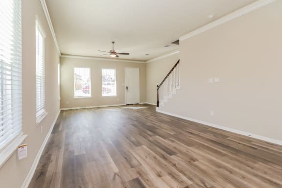 an empty living room with wood flooring and a ceiling fan