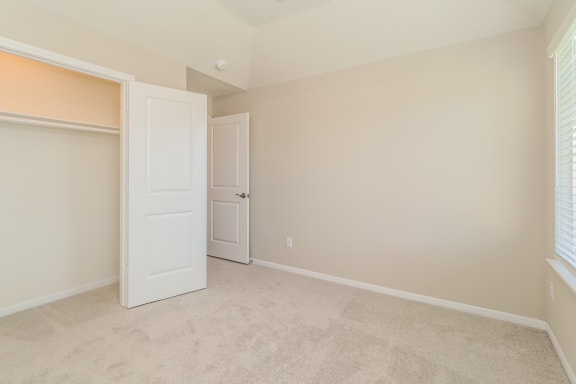 an empty bedroom with a closet and an open door