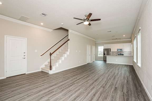 A spacious room with a staircase and a ceiling fan.