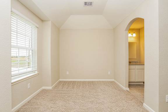A room with a carpeted floor and a window with blinds.