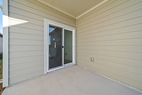A patio with a sliding glass door and a white wall.