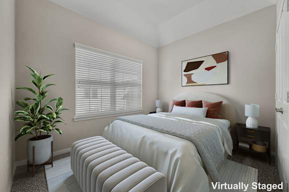 A bedroom with a bed, nightstand, and a plant.